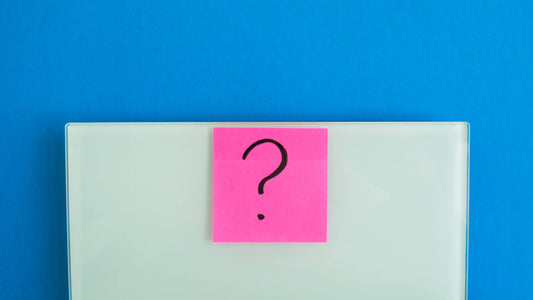 L-Theanine weight loss: Electronic scales against a blue background and a pink sticker with a question mark