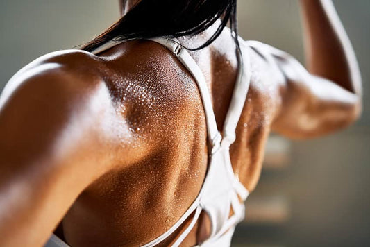 A woman’s upper back muscles flexing as she performs exercises for back thickness in the gym.