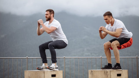 Joint recovery after workout. Men performing plyometric box jump exercises against a mountain backdrop.