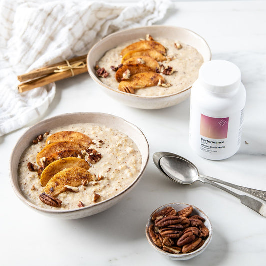 two bowls of porridge with cinnamon apples on top with Performance Lab Multi for women on the side