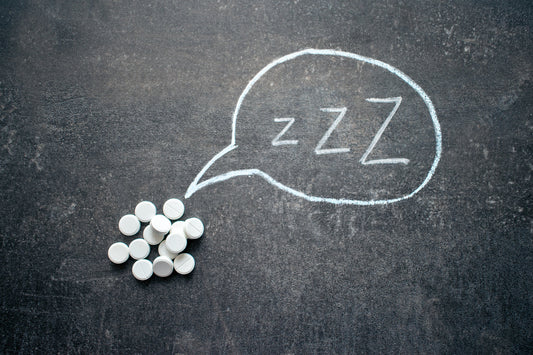 Best Vitamins for Insomnia and Sleep Deprivation. A pile of vitamins next to a chalk board with the letters Zzz on it