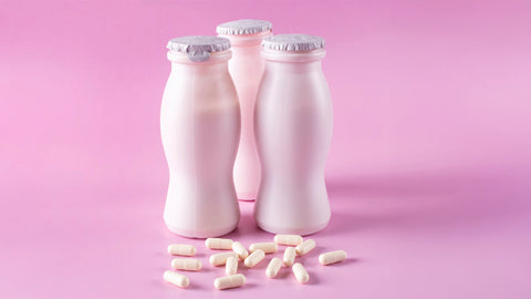 Can You Freeze Probiotics? Two bottles of milk yogurt (kefir) and capsules with probiotic on a pink background.