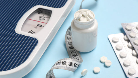 Do Iron Supplements Make You Gain Weight? A supplement bottle next to a pile of tablets sits atop a scale. 