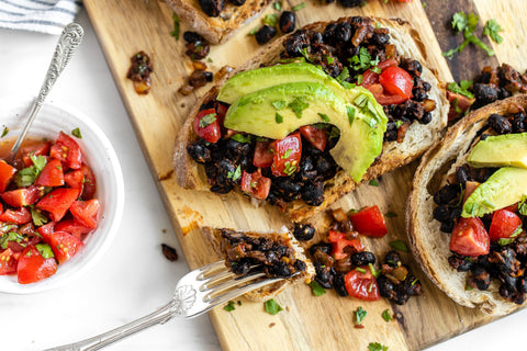 Mexican beans on toast with avocado and tomato salsa in a bowl