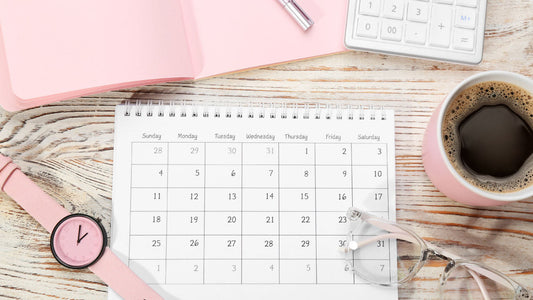 How Long to Reset Caffeine Tolerance: A Complete Guide. A mug of coffee sits on a wood tabletop next to a calendar planner, pink watch, and glasses. 