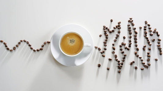 How to Stop Caffeine Jitters in 5 Easy Steps. Cup of coffee with heart rate depicted by coffee beans. The line up to the cup of coffee is steady. The line beyond the cup is messy and chaotic symbolizing jitters.
