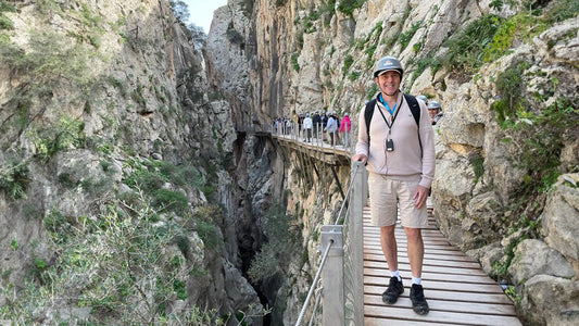 Ian walking along a narrow cliffside boardwalk through a rocky gorge during an outdoor hiking trip.