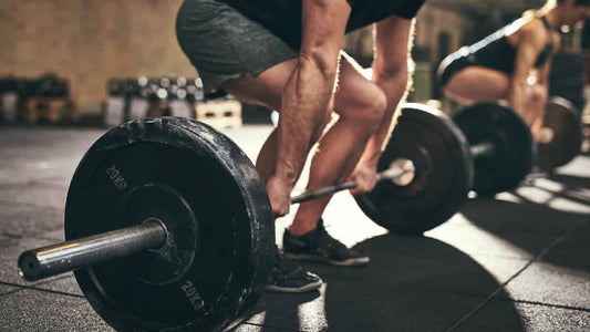 A muscular man weight training in in the gym. Conveys the question of whether it is ok ‘lifting weights on an empty stomach’