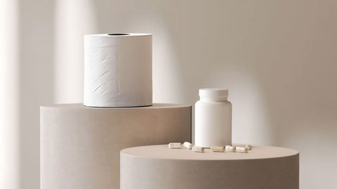 Pedestals with a toilet roll on the top one and a magnesium supplement on the next one. Suggests taking magnesium for constipation is a good idea