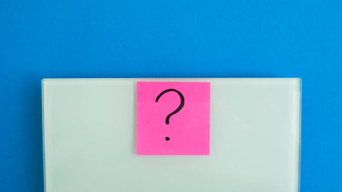 L-Theanine weight loss: Electronic scales against a blue background and a pink sticker with a question mark