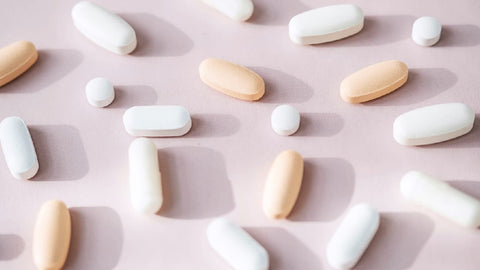 Multiple types of magnesium pills in different shapes and against a pink background. Suggesting the question of What Type of Magnesium Do I Need?