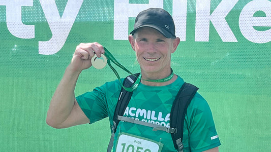 Paul smiling and holding his charity hike medal after completing a long-distance Yorkshire Dales hike while wearing a green event T-shirt and backpack.