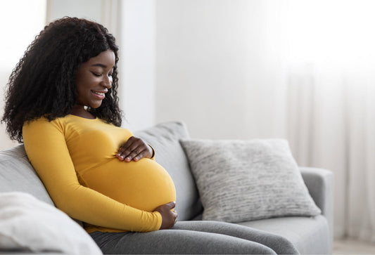 Pregnant woman sitting on a couch holding her belly