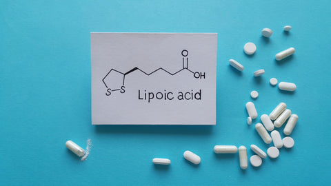 R-Lipoic Acid vs Alpha-Lipoic Acid: Which Is Better? A card showing the chemical structure of lipoic acid is surrounded by ALA capsules, caplets and tablets.