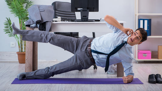 Taking Pre-Workout Before Work: A Good Idea? A young professional wearing a tie is performing a side plank on a yoga mat in the office as he takes a call 