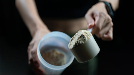 Close up of a person adding another scoop to their pre-workout shake. Conveying the point that taking too much pre workout isn’t a good thing and there are reasons to limit your dose.