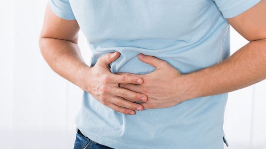 Vitamin D and Constipation: Is There a Link? A man in a blue t–shirt holds his hands over her midsection as he experiences digestive discomfort.