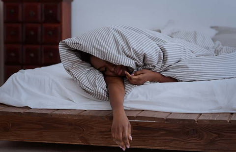 Is melatonin addictive? A woman sleeps wrapped up in a duvet