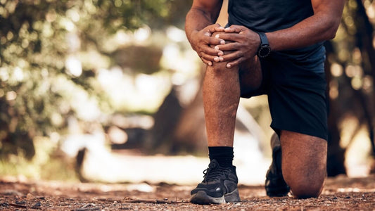 Best joint pain treatment. Man kneeling outdoors with one hand on his knee.