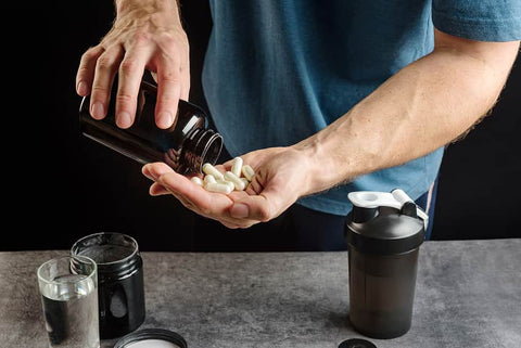 Can I take iron and vitamin D together? Man with a hand full of supplement capsules.