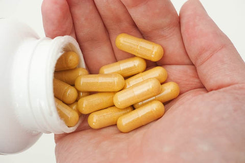 Boswellia and Turmeric: Understanding the Connection. A hand of man putting pills from a bottle into his hand.