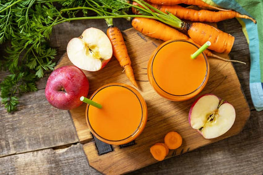 Top 8 Immune boosting Juices. Two glasses of carrot juice alongside apples and carrots