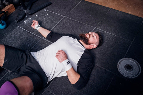 Can Pre Workout Make You Nauseous? Man lying exhausted on a gym floor.