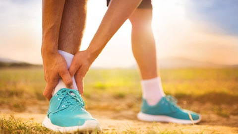 Can glucosamine cause joint pain? A runner outdoors holding their ankle, indicating joint pain or a possible sprain.