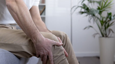 Close-up of a man gripping his sore knee, symbolizing joint discomfort possibly linked to iron deficiency.