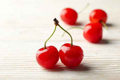Tart cherry juice for muscle recovery. Close-up of two fresh red cherries with water droplets.