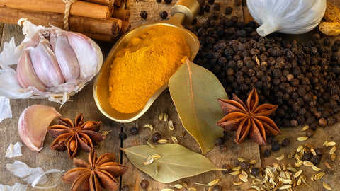 Herbal for anti inflammatory activity: how to use herbs to help combat inflammation. Assorted spices and several herbs arranged on a rustic surface with turmeric, garlic, and whole spices.
