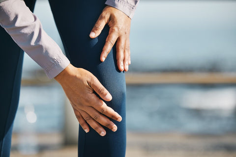 Pain on Joint. Close-up of person holding painful knee outdoors.