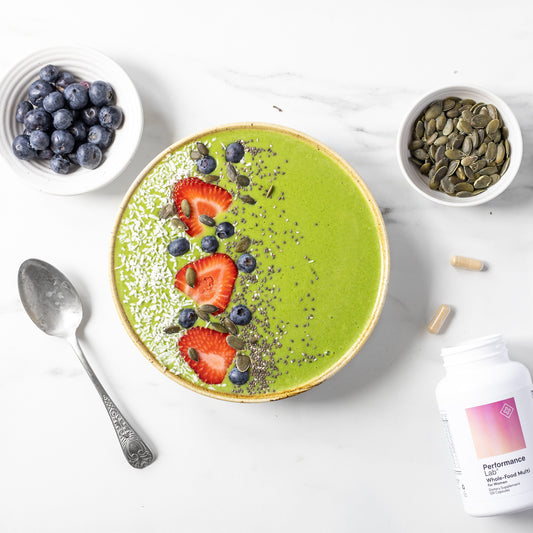 Green smoothie bowl with berries and seeds and bowl of blueberries and multi on the side.