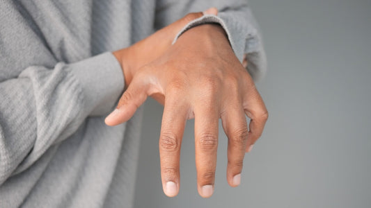 Sore joint in finger: a close-up of a person holding their forearm while their hand hangs limp, suggesting wrist or hand discomfort.
