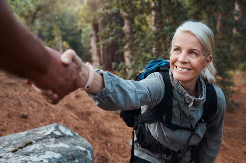Supplements for menopause joint pain. Smiling woman hiking in a forest.